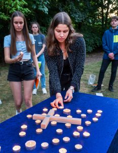 Schüler*innen mit Kerzen bei einer abendlichen Freiluftandacht.