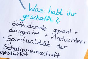 Handschriftliche deutsche Liste der schulischen Leistungen auf weißem Papier.