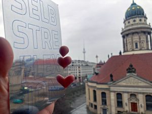 Spiegel mit Aufschrift "Selbstreflexion" vor der Skyline Berlins.