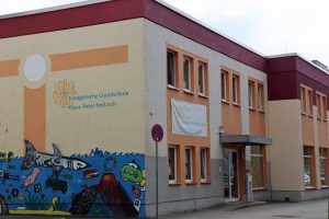 Schule mit Wandgemälde mit Hai, Fisch und U-Boot; auf den Schildern steht Evangelische Grundschule Klaus-Peter Hertzsch.