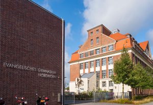 Evangelisches Gymnasium Nordhorn Backsteinbau neben einer großen Schule mit rotem Ziegeldach.