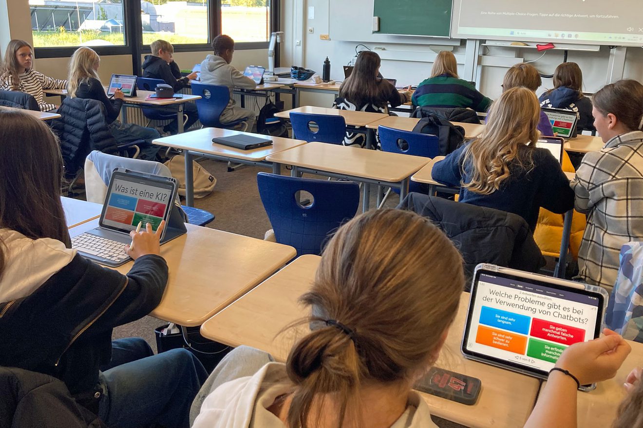 Die Schüler verwenden im Unterricht Laptops; auf den Bildschirmen werden deutsche Aufgaben zu Chatbots und KI angezeigt. Foto: Anne Broy, Wilhelm-Löhe-Schule Nürnberg