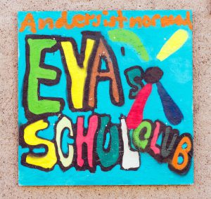 Auf einem Schild im Graffiti-Stil steht „Anders ist normal. EYA’s Schulclub“ zusammen mit einer Propeller-Grafik. Foto: Martin Kirchner